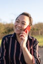 An Asian Filipino woman happily talks on the phone during sunset. Close-up shot portrait