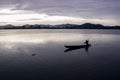 Asian fisherman boating across lake