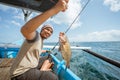 Asian fisherman catches grouper in the sea while fishing