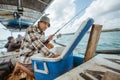 Asian fisherman checking bait in box in small fishing boat