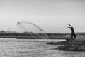 Asian Fisherman throwing a net for catching freshwater fish in the early morning