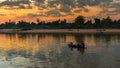 Asian fisherman on wooden boat casting a net for catching freshwater fish Royalty Free Stock Photo