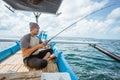 Asian fishermen holding fishing rods while casting at sea