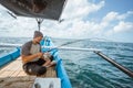 Asian fishermen pull in fishing rods during hook ups