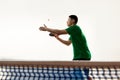 Asian, fit man, professional table tennis player in green sportwear serving ball in motion against white studio