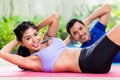 Asian fitness couple doing sit-up in tropical home