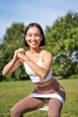 Asian fitness girl doing squats in park, using resistance band, stretching yoga rope for workout training on fresh air Royalty Free Stock Photo