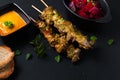 Asian food concept homemade beef satay grilled and spicy peanut spice sauce on black slate board with copy space