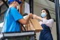 Asian Food deliverly man wear protective mask due to Covid-19 pandemic, show online order on phone to restaurant worker at coffee