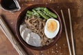 Asian food ramen noodles with meat, vegetables and egg in a brown bowl on a wooden board Royalty Free Stock Photo