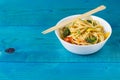 Asian food. Stir fry udon noodles with vegetables on a white bowl, blue wooden backgound, cooked in wok, copy space Royalty Free Stock Photo