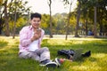 Asian freelance man sitting in a park using his phone on a comfortable working day Royalty Free Stock Photo