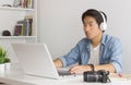 Asian Freelance Videographer Checking Multimedia Sound by Laptop in Home Office