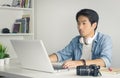 Asian Freelance Videographer Work from Home Editing Multimedia File by Laptop in Home Office in Vintage Tone