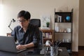 Asian freelancer business man working at home using laptop computer at workspace office desk in living room. Remote work from home Royalty Free Stock Photo