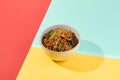 Asian fried buckwheat noodles with chicken on coloured background Fried noodles in ceramic bowl on yellow, red and blue background