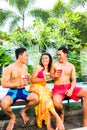 Asian friends drinking cocktails at pool Royalty Free Stock Photo