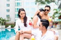 Asian Friends sitting by hotel swimming pool Royalty Free Stock Photo