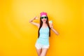 Asian funky hipster is posing for photo, wearing tourist`s outfit, glasses, hat, holds ice cream, so slim, attractive and