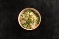 Asian garnish, boiled rice with vegetables, peas, carrots and green onions in a round plate on a black stone table. Pan-Asian and Royalty Free Stock Photo