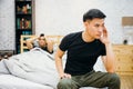 Asian gay couple having argument with each other in bedroom. Thoughtful gay man having stress while another is sleeping Royalty Free Stock Photo