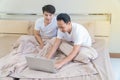 Asian gay couple sitting on the bed using laptop Royalty Free Stock Photo