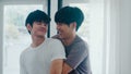 Asian Gay couple standing and hugging near the window at home. Young Asian LGBTQ+ men kissing happy relax rest together spend