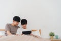 Asian Gay couple using tablet at home. Young Asian LGBTQ men happy relax rest together after wake up, check mail and social media