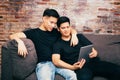 Asian gay couple watching and looking at phone tablet together. Portrait of happy gay men - Homosexual love concept.