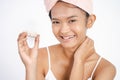 asian girl applying facial moisturizer while holding jar Royalty Free Stock Photo