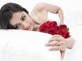 Asian girl in bed with red roses Royalty Free Stock Photo