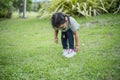 Asian girl bends down to put on shoes by herself in the backyard while doing mom and dad family vacation activities