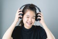 Asian girl in black casual dress listening to music from black headphones. In a comfortable and good mood. Royalty Free Stock Photo