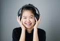 Asian girl in black casual dress listening to music from black headphones. In a comfortable and good mood. Royalty Free Stock Photo