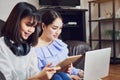 Asian girl in blue casual dress listening to music from black headphones and use laptop. Royalty Free Stock Photo