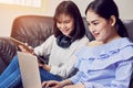 Asian girl in blue casual dress listening to music from black headphones and use laptop. Royalty Free Stock Photo