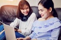 Asian girl in blue casual dress listening to music from black headphones and use laptop. In a comfortable and good mood. Royalty Free Stock Photo