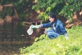 Asian girl collecting garbage and plastic on the river to dumped into the trash for recycle.