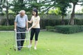 Asian girl daughter take care of disabled senior grandfather in garden. Attractive young woman help and support elderly older man Royalty Free Stock Photo