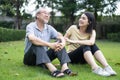 Asian girl daughter take care of senior elderly grandfather in garden. Attractive young beautiful woman and older mature man