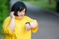 Asian girl with Down syndrome watch fitness watch happy smile By walking to burn fat and jogging slowly to exercise in a park in