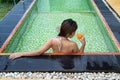 Asian Girl Drinking Glass Of Orange Juice In The Pool