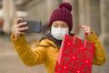 Asian girl enjoying Christmas shopping during covid19 - young happy and beautiful Chinese woman holding red shopping bag taking Royalty Free Stock Photo