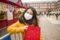Asian girl enjoying Christmas shopping during covid19 - young happy and beautiful Chinese woman with mask holding red shopping bag Royalty Free Stock Photo