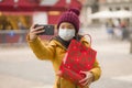 Asian girl enjoying Christmas shopping during covid19 - young happy and beautiful Japanese woman holding red shopping bag taking Royalty Free Stock Photo