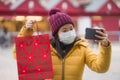 Asian girl enjoying Christmas shopping during covid19 - young happy and beautiful Japanese woman holding red shopping bag taking Royalty Free Stock Photo