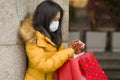 Asian girl enjoying Christmas shopping during covid19 - young happy and beautiful Korean woman with mask holding red shopping bag Royalty Free Stock Photo