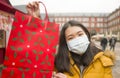 Asian girl enjoying Christmas shopping during covid19 - young happy and beautiful Korean woman with mask holding red shopping bag Royalty Free Stock Photo