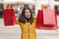 Asian girl enjoying Christmas shopping - young happy and beautiful Chinese woman holding red shopping bag buying presents at Royalty Free Stock Photo