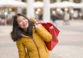 Asian girl enjoying Christmas shopping - young happy and beautiful Chinese woman holding red shopping bag buying presents at Royalty Free Stock Photo